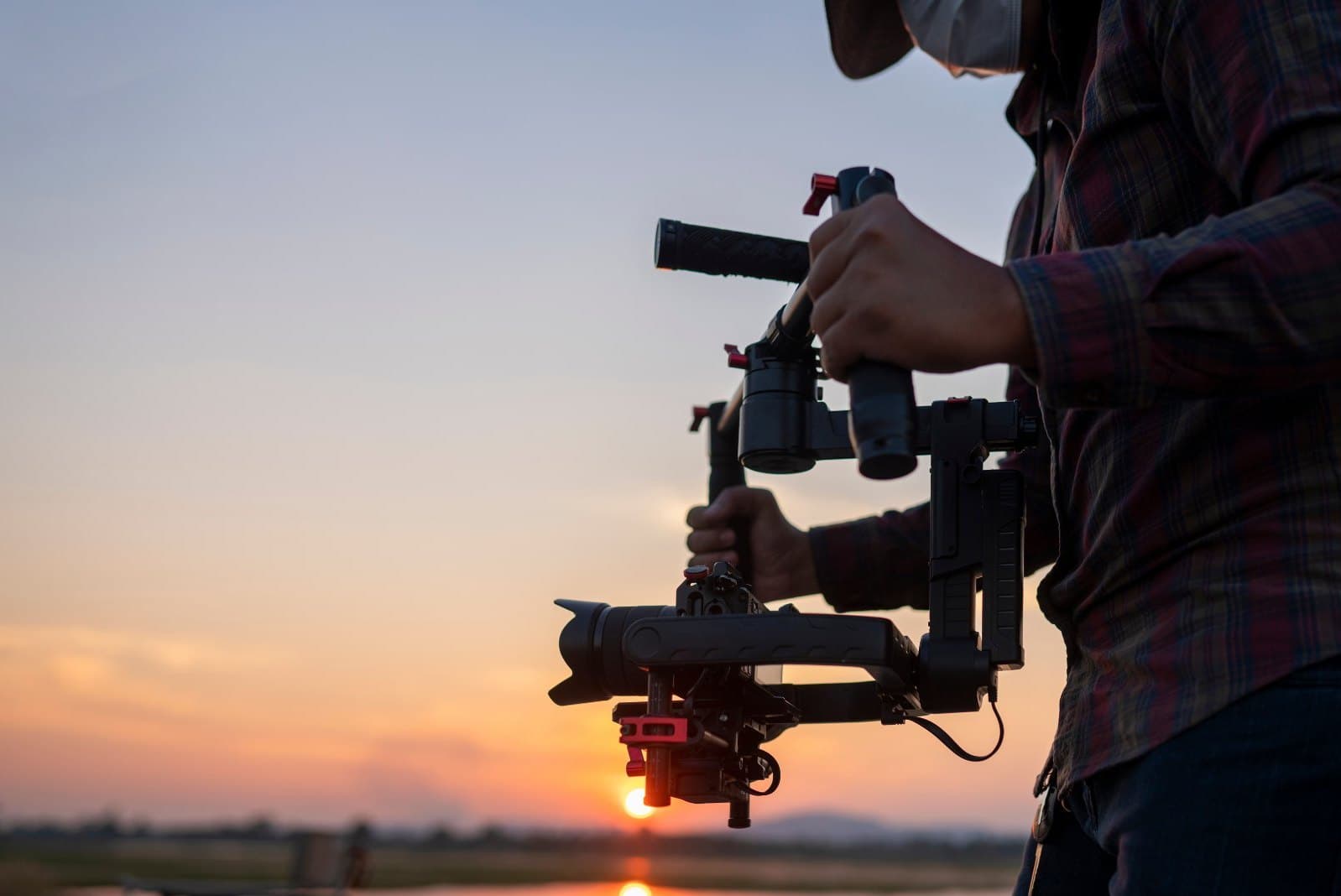 Camera operator filming with a gimbal at sunset